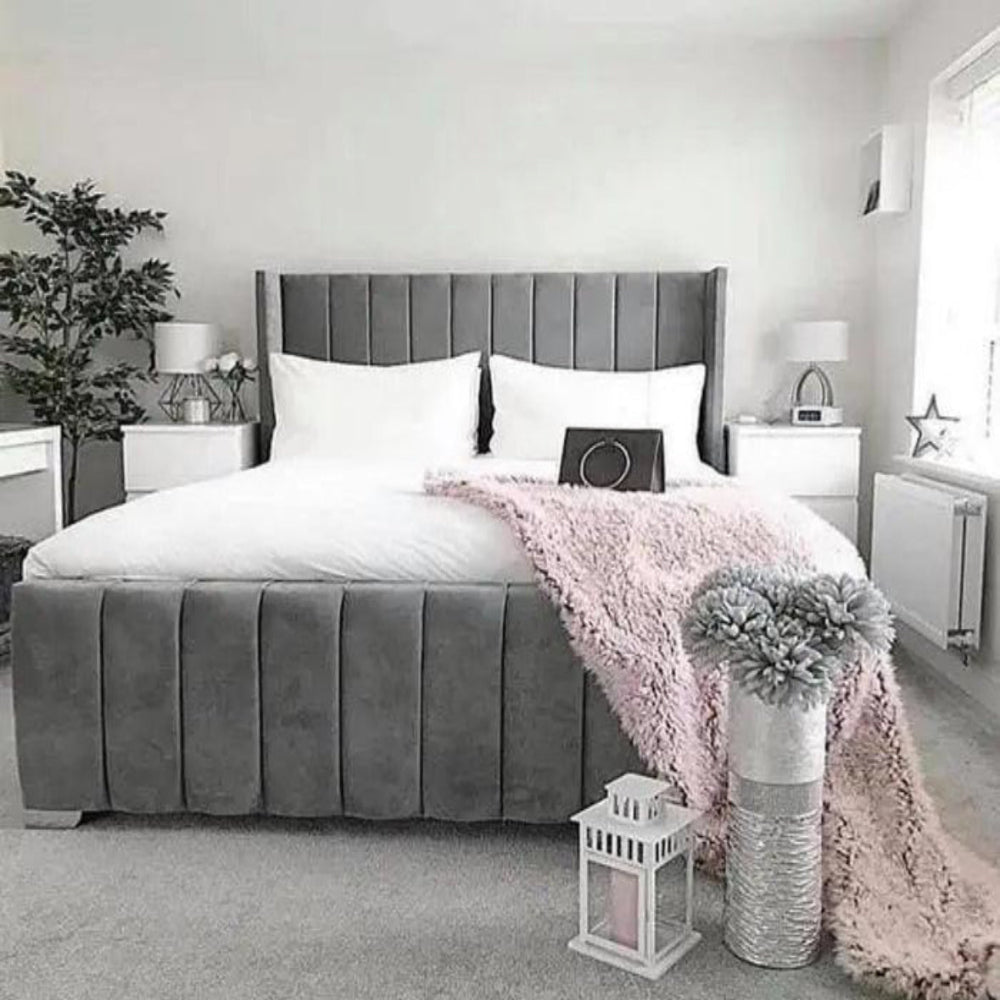 A modern bedroom featuring a gray Ella paneled wingback bed with white bedding, pink throw, and minimal decor.