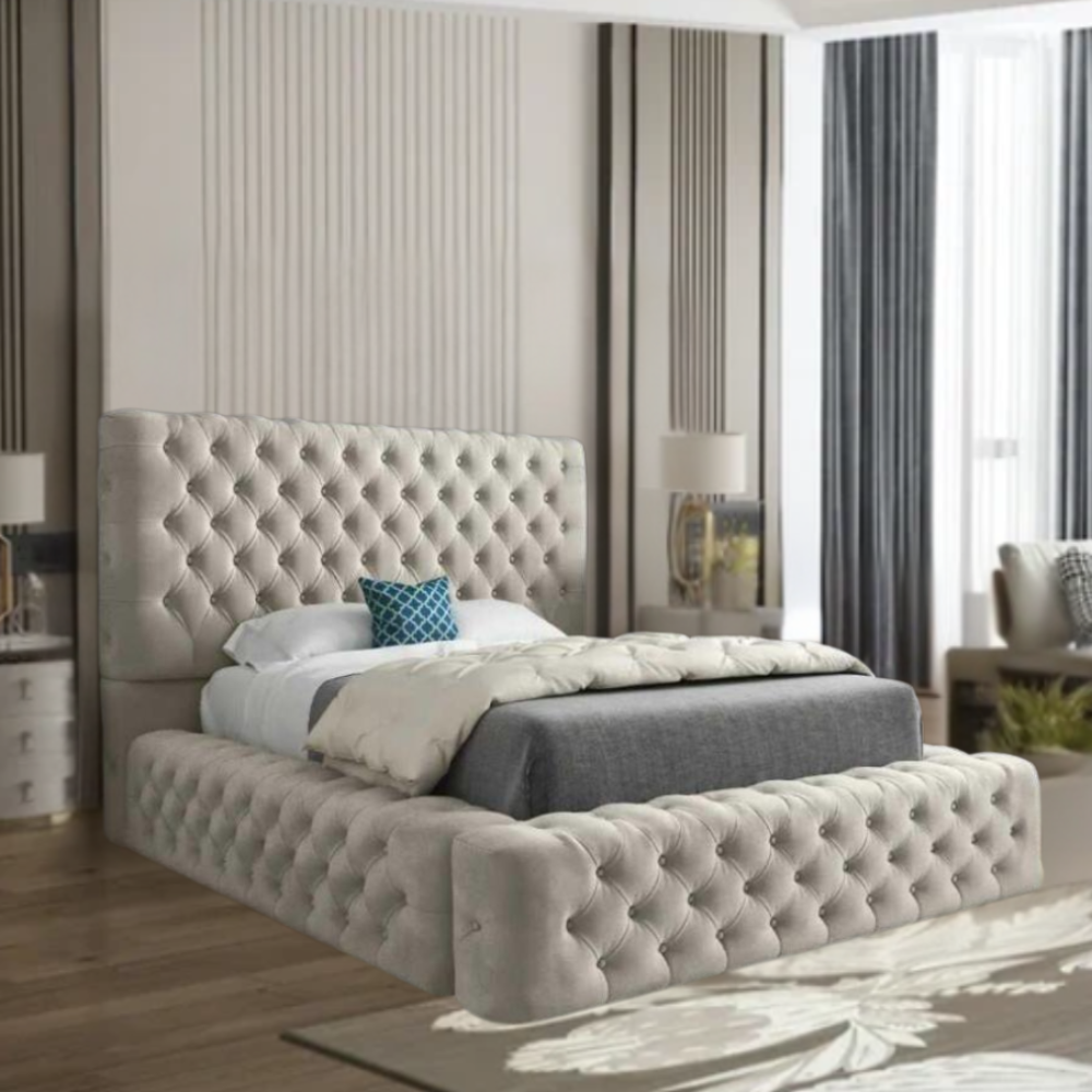 A modern bedroom with a large tufted beige MillyAmbassado bed, gray and white bedding, teal accent pillow, and mirrored nightstands with lamps.