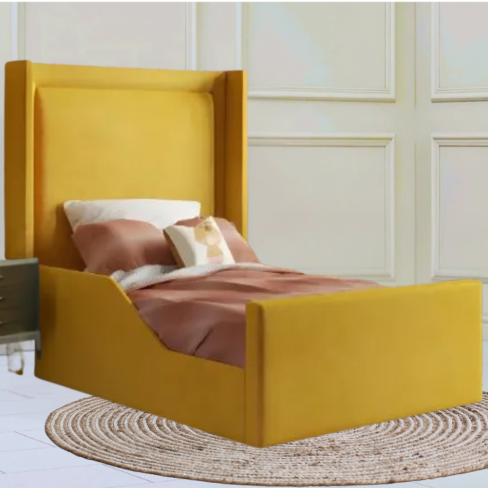 A bedroom with a yellow upholstered Zayn Wingback bed, pinkish-brown bedding, a wooden nightstand, and a blue lamp.