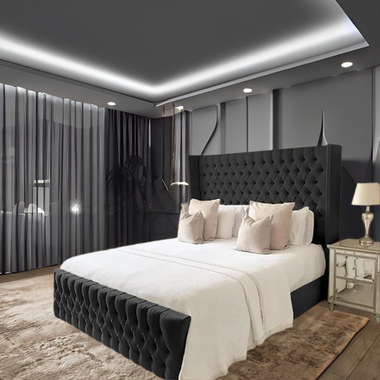 Modern bedroom with a black tufted  acewingback bed, white linens, mirrored nightstand, and sheer curtains.